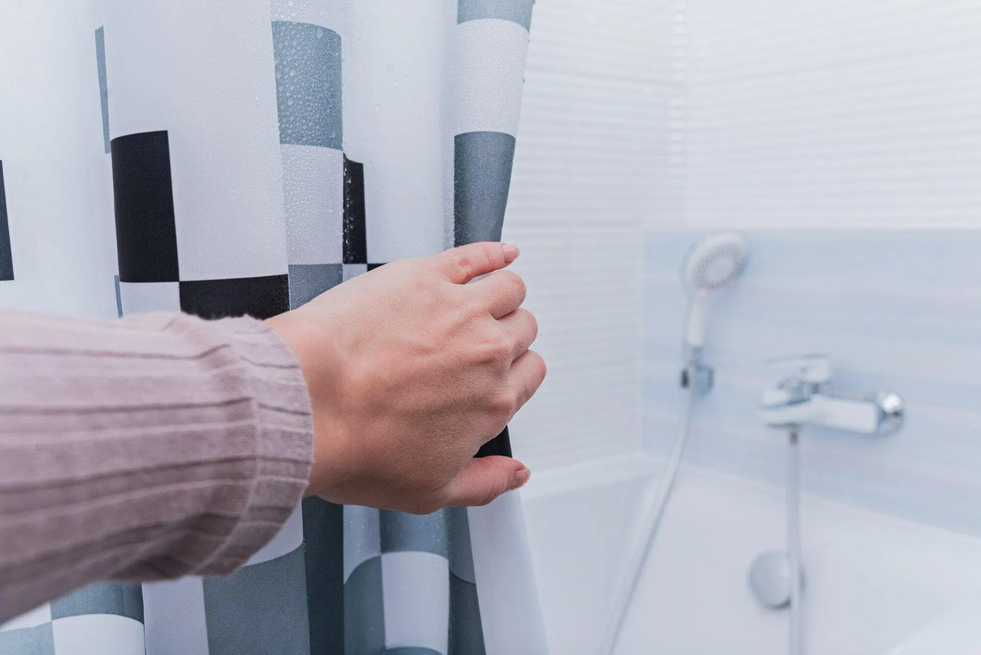 Hand pulling shower curtain left